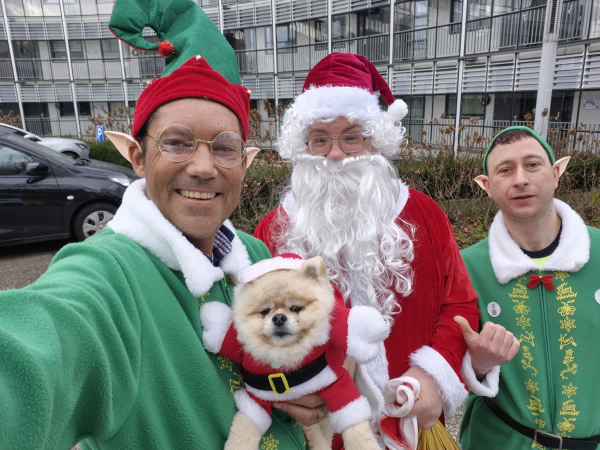 De kerstman met twee kerstelfen en het hondje